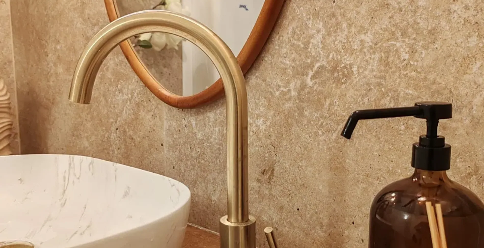 Détail d'une cabine : vasque de marbre, robinet doré et travertin